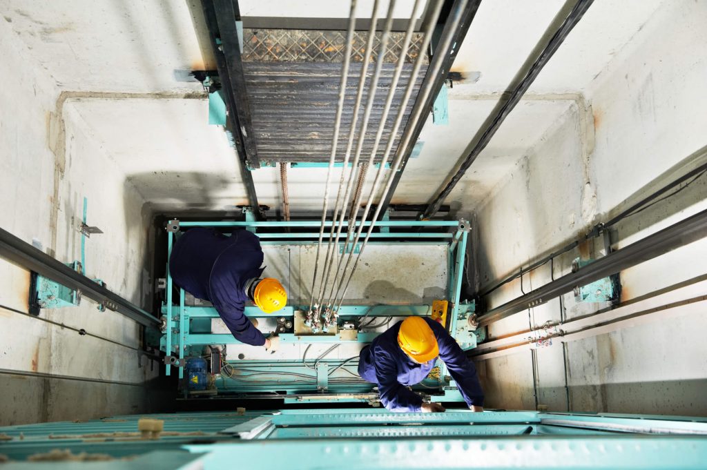 Engenheiros fazendo a manutenção preventiva de um elevador